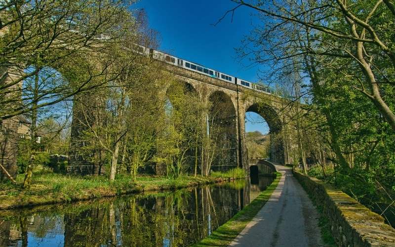 A train crossing the Saddleworth viaduct above the canal towpath near Uppermill, Oldham