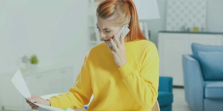 Person on the phone to their network while reading a paper bill