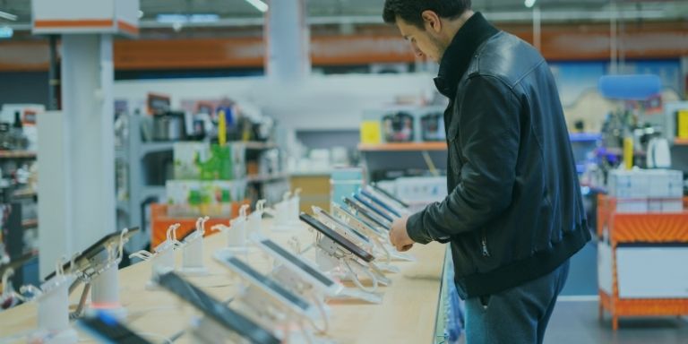 Person comparing phones on display in an electronics shop